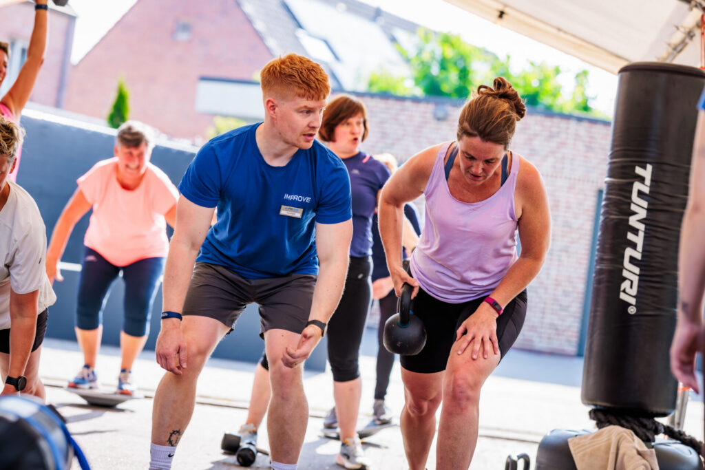 Trainer begeleidt een groepsles bij IMPROVE Malle.